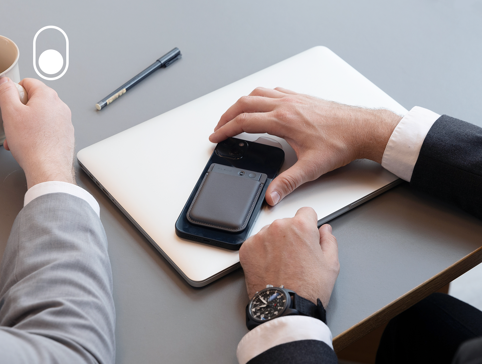 Schwarzer Plaud Note auf einem Smartphone, das auf einem Laptop liegt, in einer professionellen Büroumgebung.
