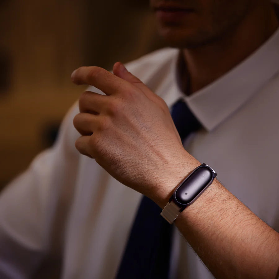 Ein Mann im Business-Outfit trägt den schwarzen Plaud NotePin an einem silbernen Armband am Handgelenk.