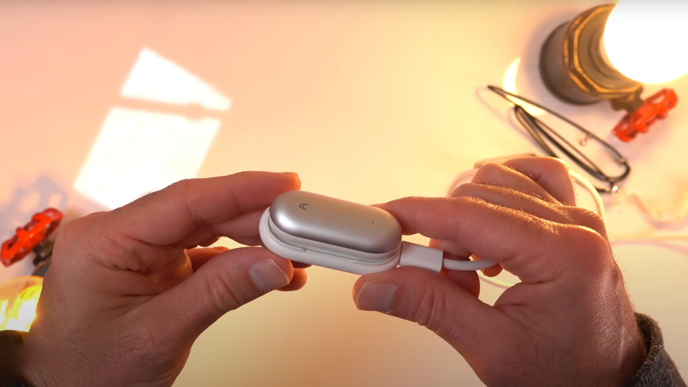 Ein silbernes Plaud NotePin wird in einer weißen Ladestation per USB-C-Kabel aufgeladen.