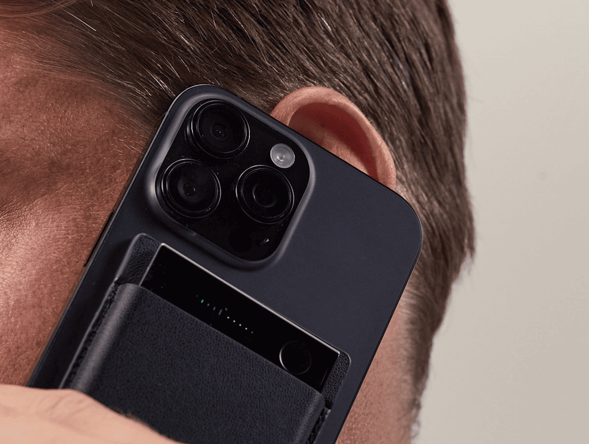 Schwarzer Plaud Note Pro an der Rückseite eines Smartphones befestigt, während ein Nutzer telefoniert.