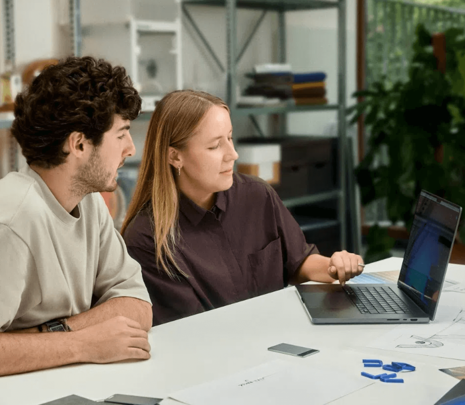 Zwei Personen arbeiten am Laptop mit einem silbernen Plaud Note Pro auf dem Tisch.